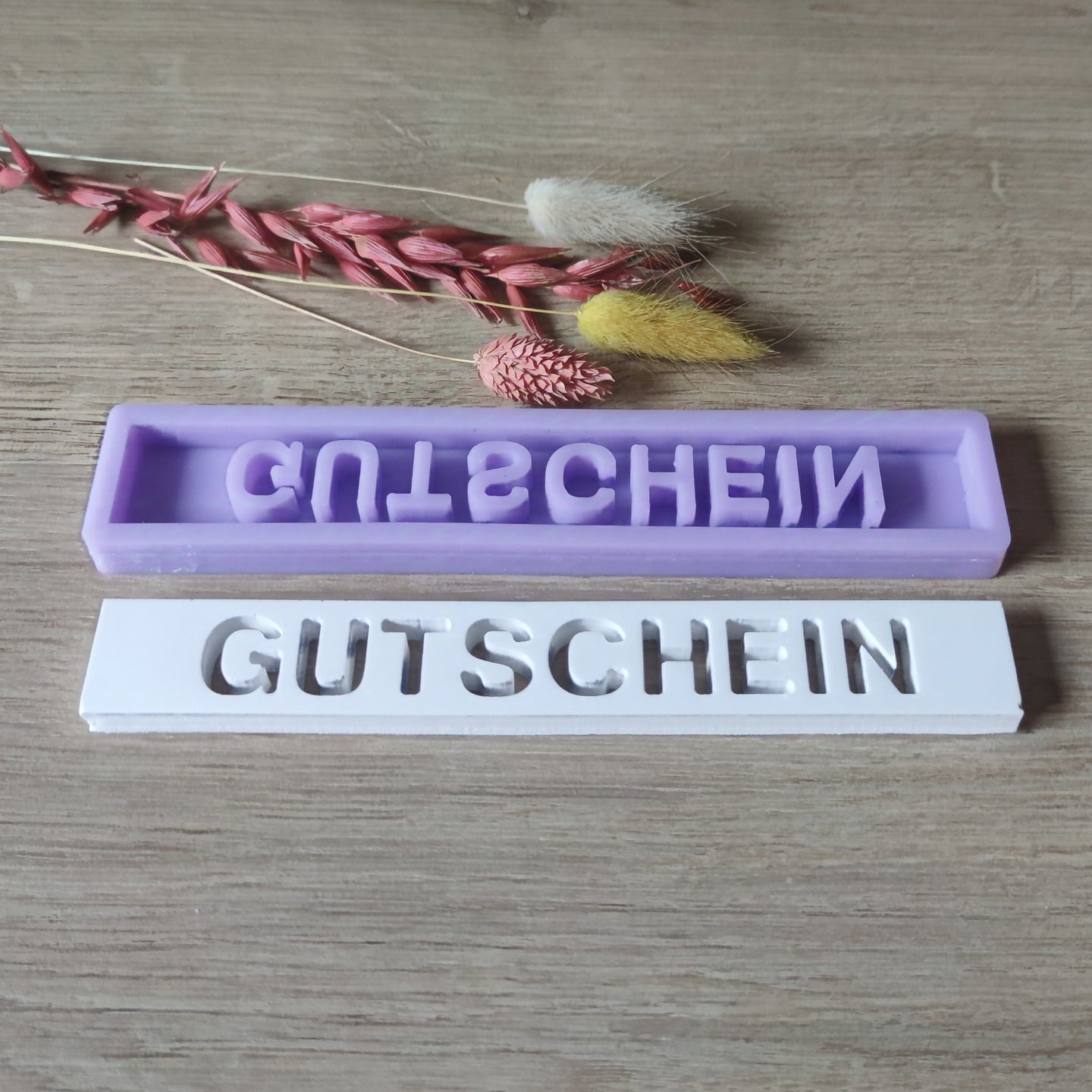 Easy-Sticks Silikonform "Gutschein" - Detailansicht der lila und weißen Gießformen, perfekt für individuelle Geschenkideen, zusammen mit dekorativen Pflanzen.