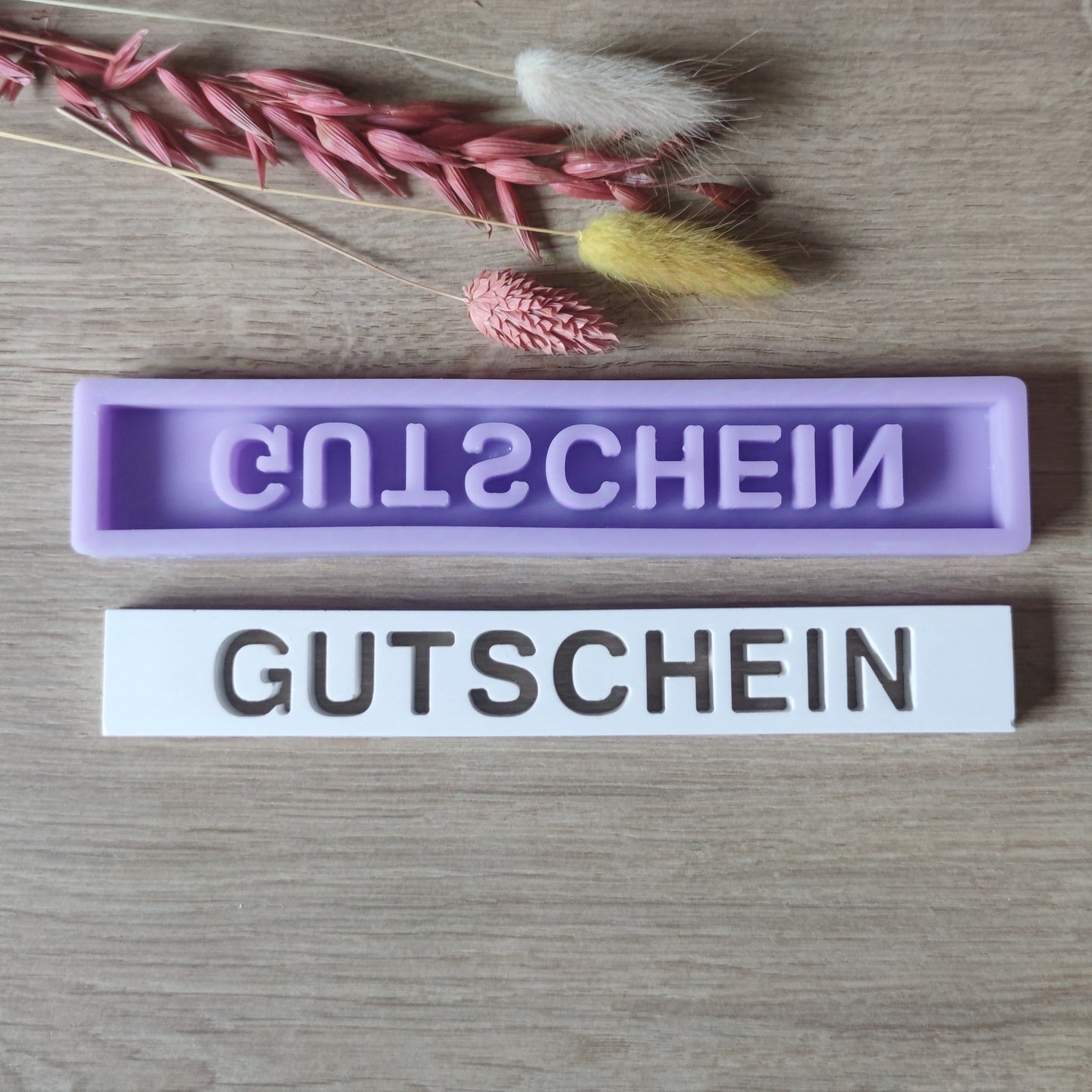 Easy-Sticks Silikonform "Gutschein" - Kreative Gießform in lila und weiß, ideal zum Gestalten persönlicher Geschenke, umgeben von Trockenblumen.