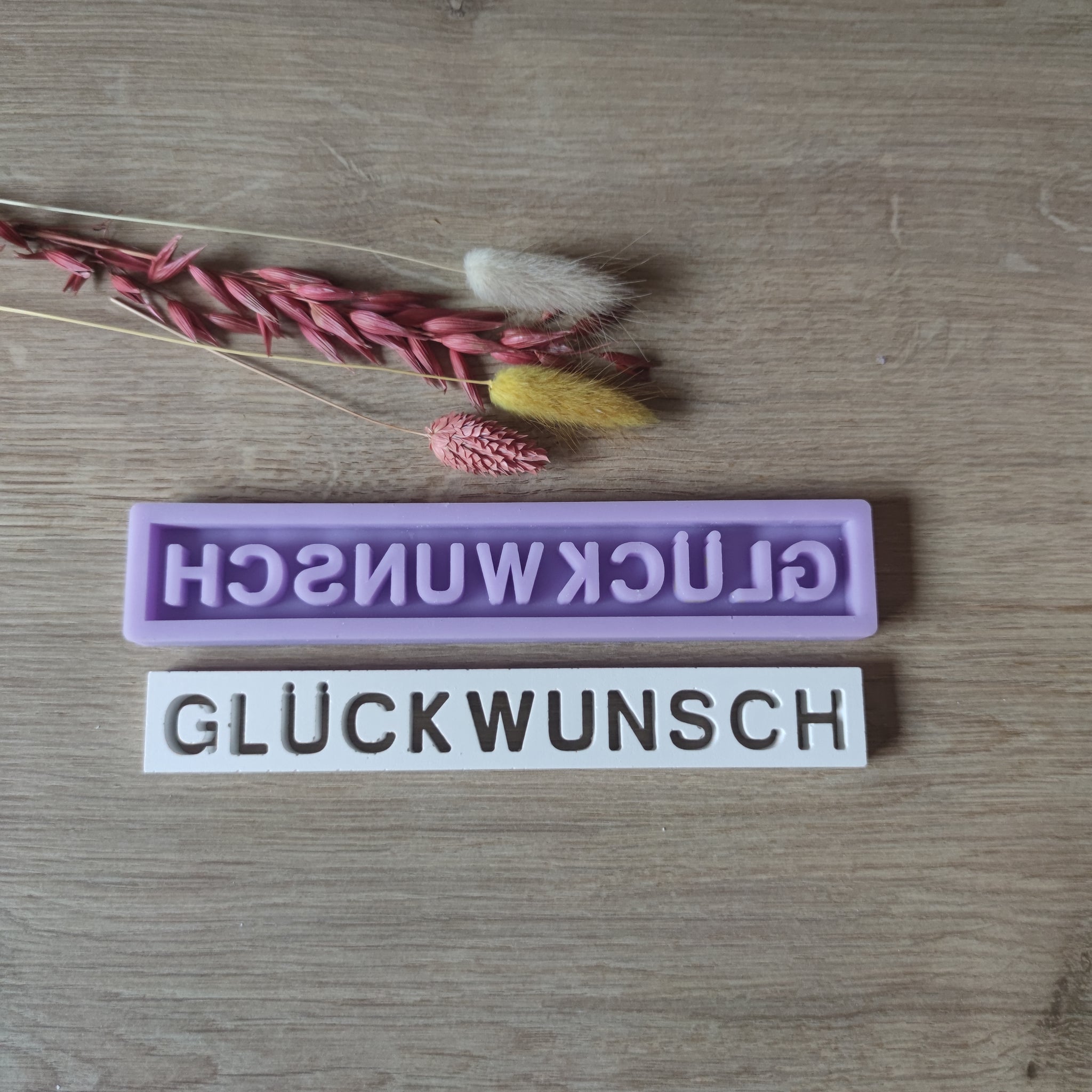 Detailaufnahme der Silikonform 'GLÜCKWUNSCH' von Easy-Sticks, die in zwei Farben dargestellt wird. Perfekt für individuelle Geschenke und Dekorationen.