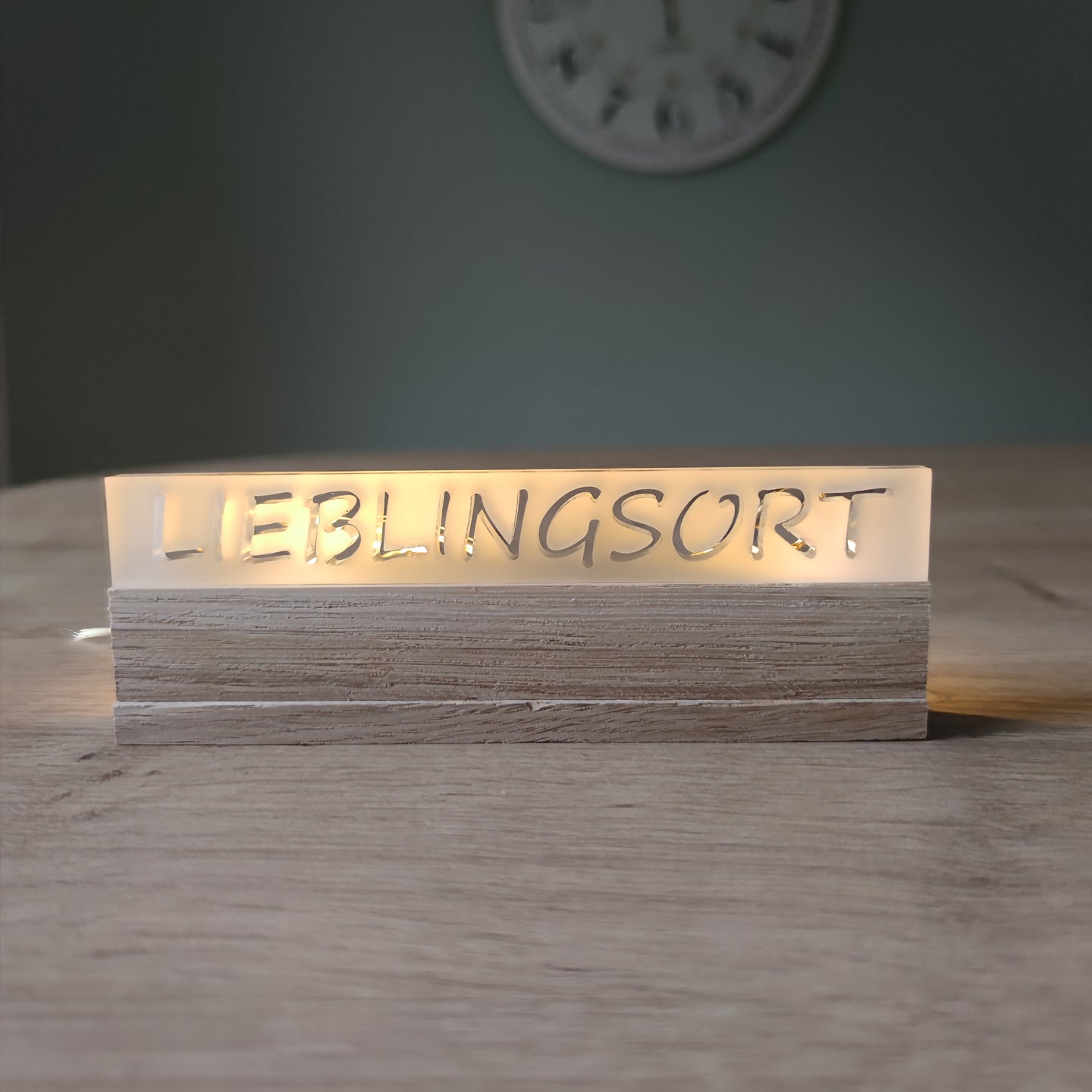 Beleuchteter Acrylschriftzug 'LIEBLINGSORT' auf einem Holzsockel, ideal für Dekoration. Easy-Sticks Acryl Satiniert.