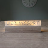 Beleuchteter Acrylschriftzug 'LIEBLINGSORT' auf einem Holzsockel, ideal für Dekoration. Easy-Sticks Acryl Satiniert.