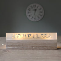 Sapf auf einem Tisch mit dem Schriftzug 'HIP HIP HURRA' aus satiniertem Acryl von Easy-Sticks, ideal für Feierlichkeiten und besondere Anlässe.