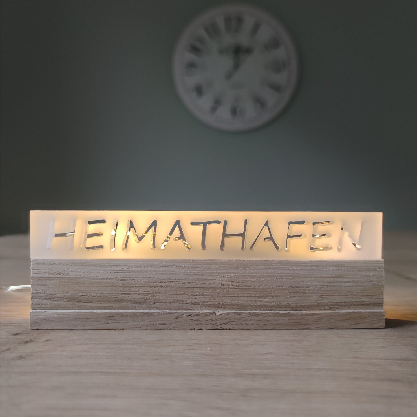 Beleuchtetes Acrylschild mit dem Schriftzug "HEIMATHAFEN" von Easy-Sticks, elegant präsentiert auf einem Holzsockel.