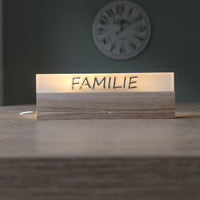 Stilvolle Acryl Easy-Sticks "Familie" von Easy-Sticks, elegant beleuchtet und auf einem Holzsockel präsentiert. Ideal für Wohnräume und kreative Dekoration.
