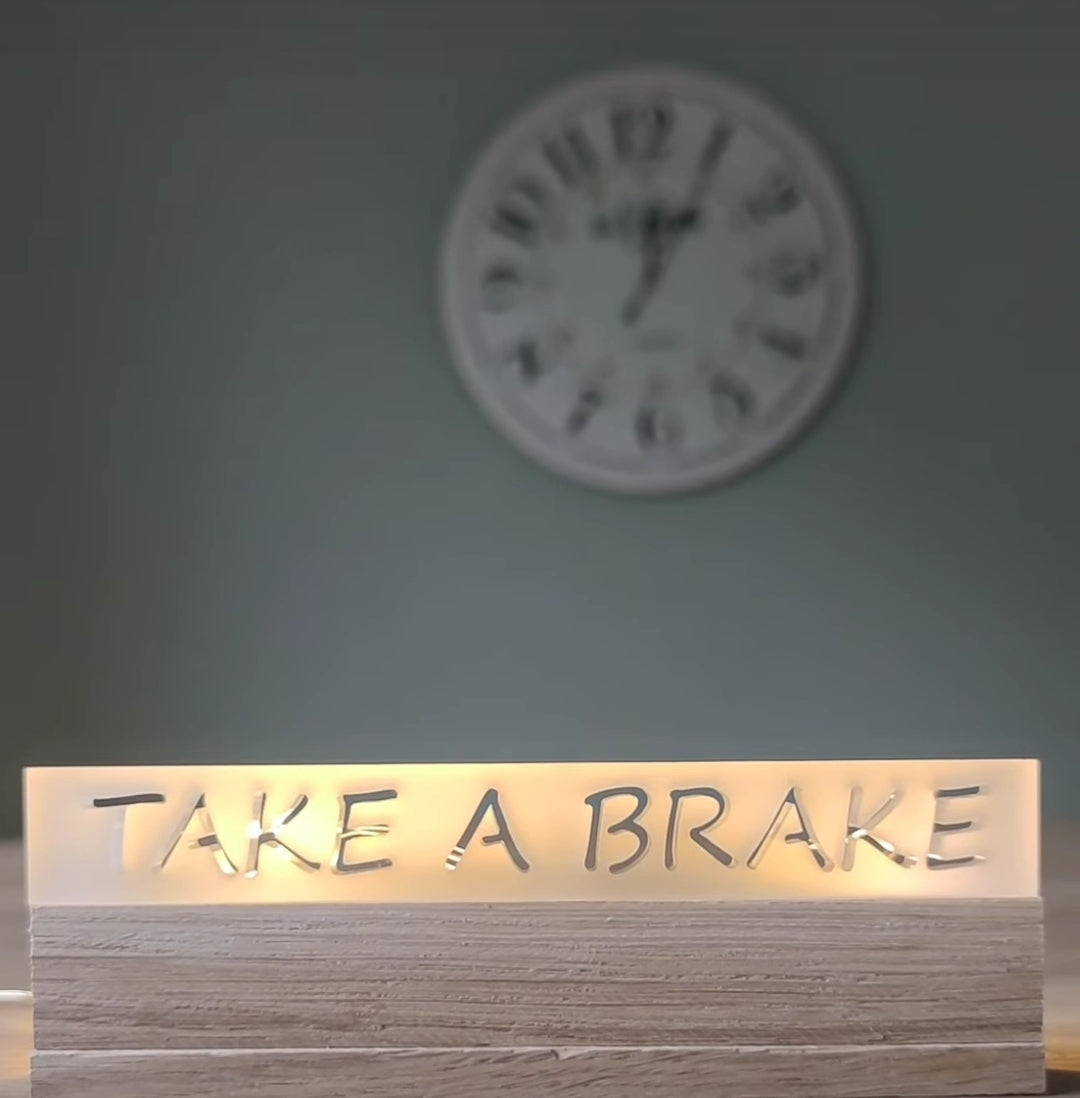 Acryl Easy-Sticks 'Take a Brake' von Easy-Sticks, stilvolle Deko mit sanft leuchtendem Schriftzug auf hellem Holzuntergrund, perfektes Wohnaccessoire für ein kreatives Zuhause.