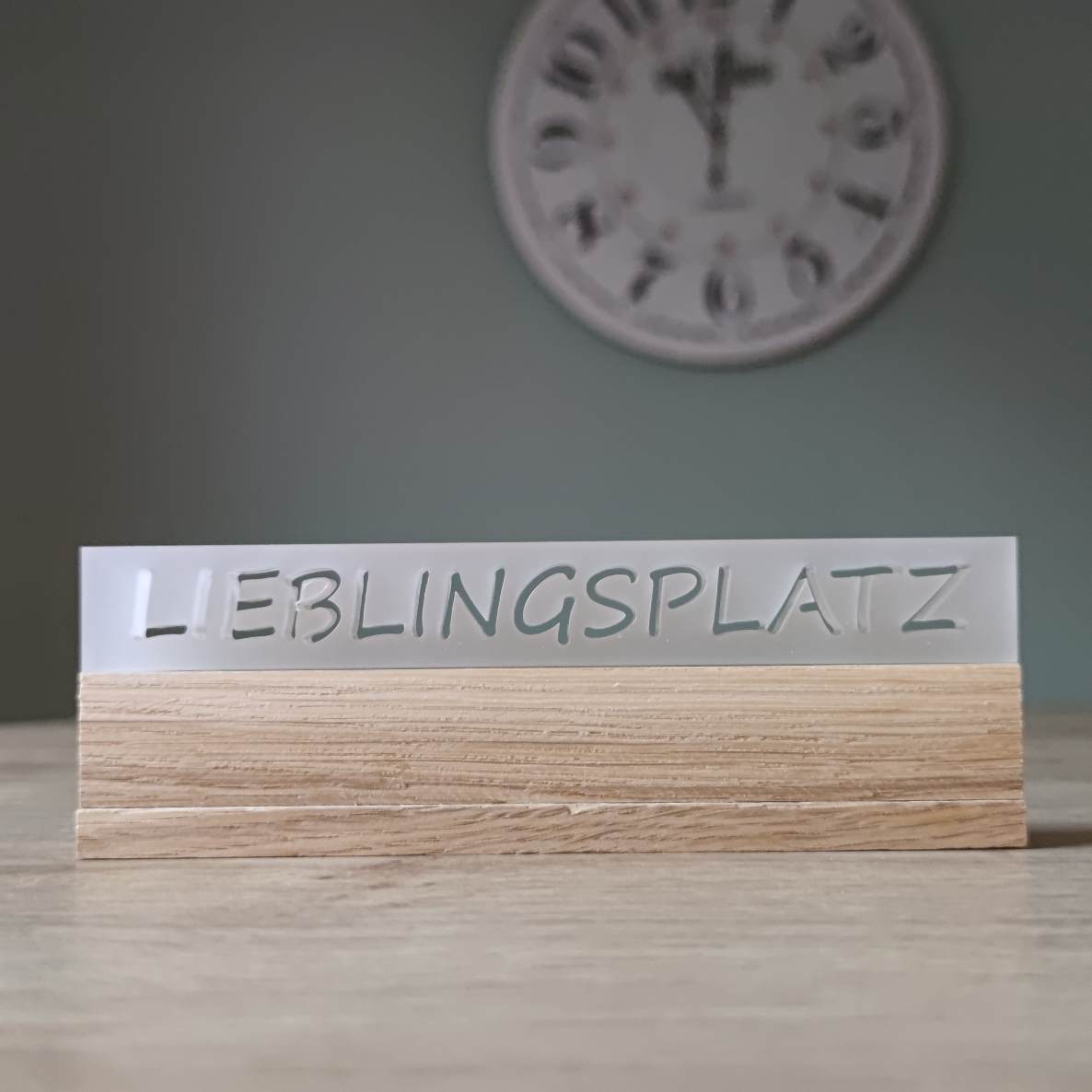 Eleganter Acryl-Easy-Stick mit dem Schriftzug 'LIEBLINGSPLATZ', von Easy-Sticks, auf einem Holzuntergrund platziert, perfekt für die dekorative Gestaltung in jedem Raum.