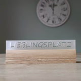 Eleganter Acryl-Easy-Stick mit dem Schriftzug 'LIEBLINGSPLATZ', von Easy-Sticks, auf einem Holzuntergrund platziert, perfekt für die dekorative Gestaltung in jedem Raum.