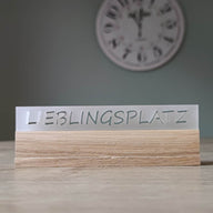 Eleganter Acryl-Easy-Stick mit dem Schriftzug 'LIEBLINGSPLATZ', von Easy-Sticks, auf einem Holzuntergrund platziert, perfekt für die dekorative Gestaltung in jedem Raum.
