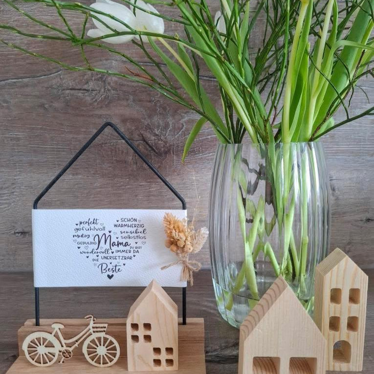 Kreative Mama-Laterne von easy-sticks mit ansprechendem Schriftzug in einem stilvollen Rahmen, umgeben von Holzdekoration und einer blühenden Pflanze.