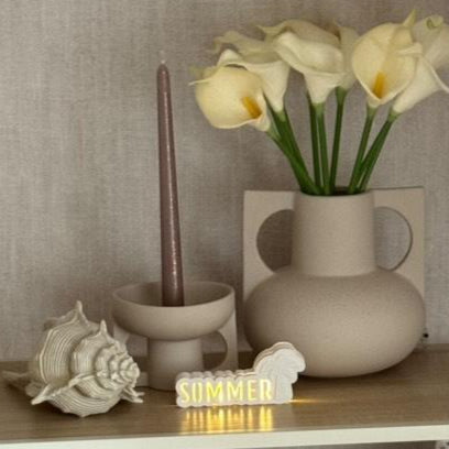 Gestellte Szene mit dem Silikonform Lichtobjekt "Sommer mit Palme" von Easy-Sticks, dekoriert neben einer Vase mit Blumen und einer Kerze, schafft eine gemütliche Sommeratmosphäre.