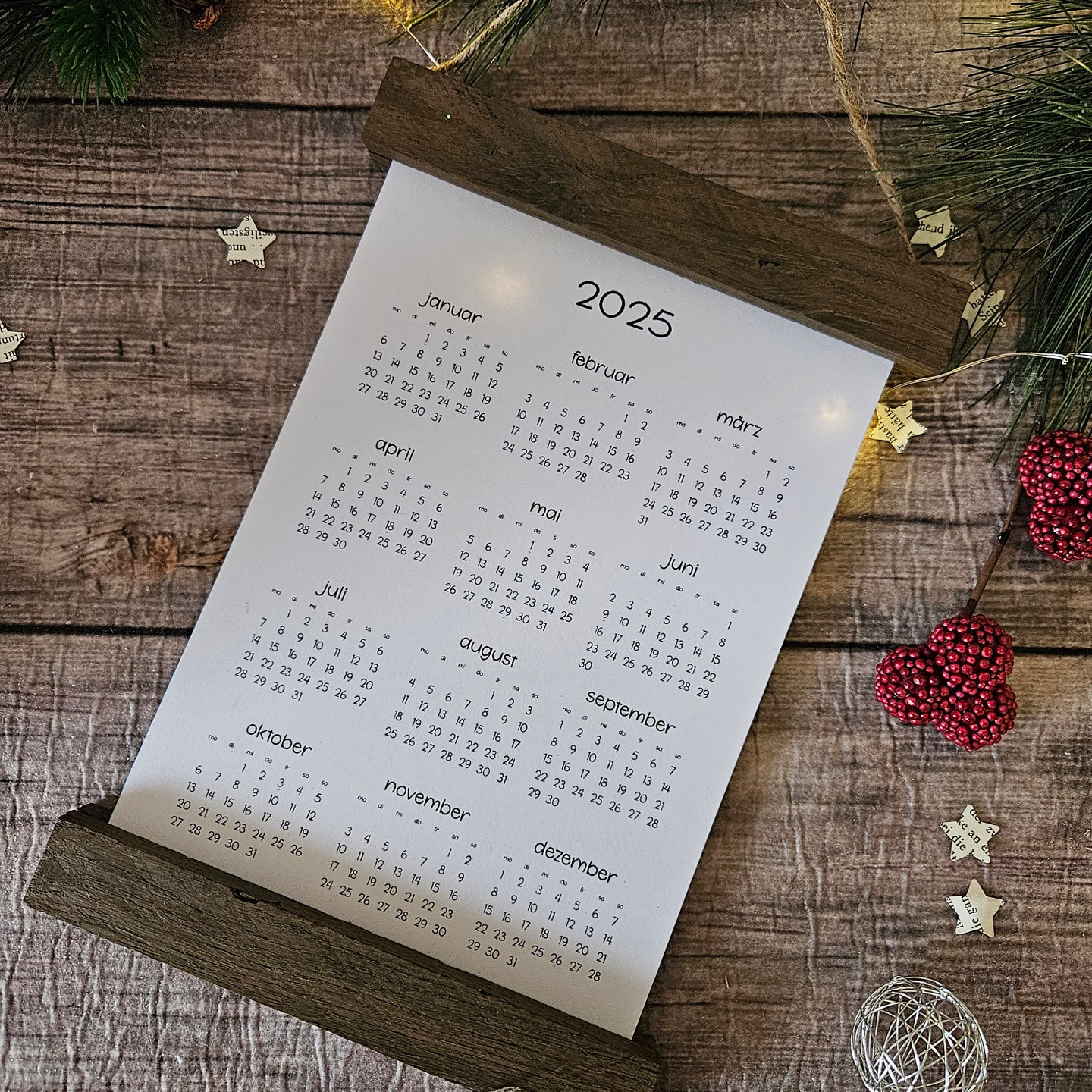 Kreativer DIY Kalender 2025 von easy-sticks, gestaltet mit einem rustikalen Holzständer und umgeben von festlichem Schmuck, ideal als persönliches Geschenk und zur Dekoration.