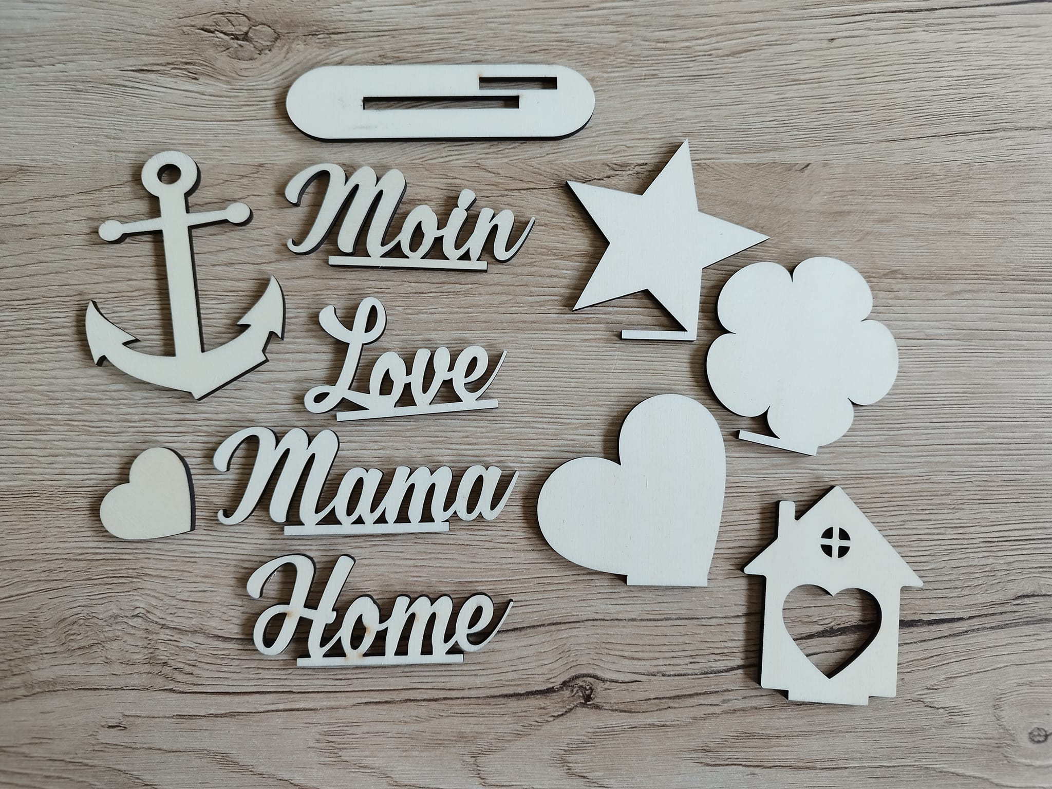 Vielfalt an Holzformen, einschließlich der Worte "Moin", "Love", "Mama" und "Home" aus den Ausstechern "3 & 4mm Ausstecher Home, Moin, Herz, Mama, Love" von easy-sticks. Perfekt für kreative Bastelideen.
