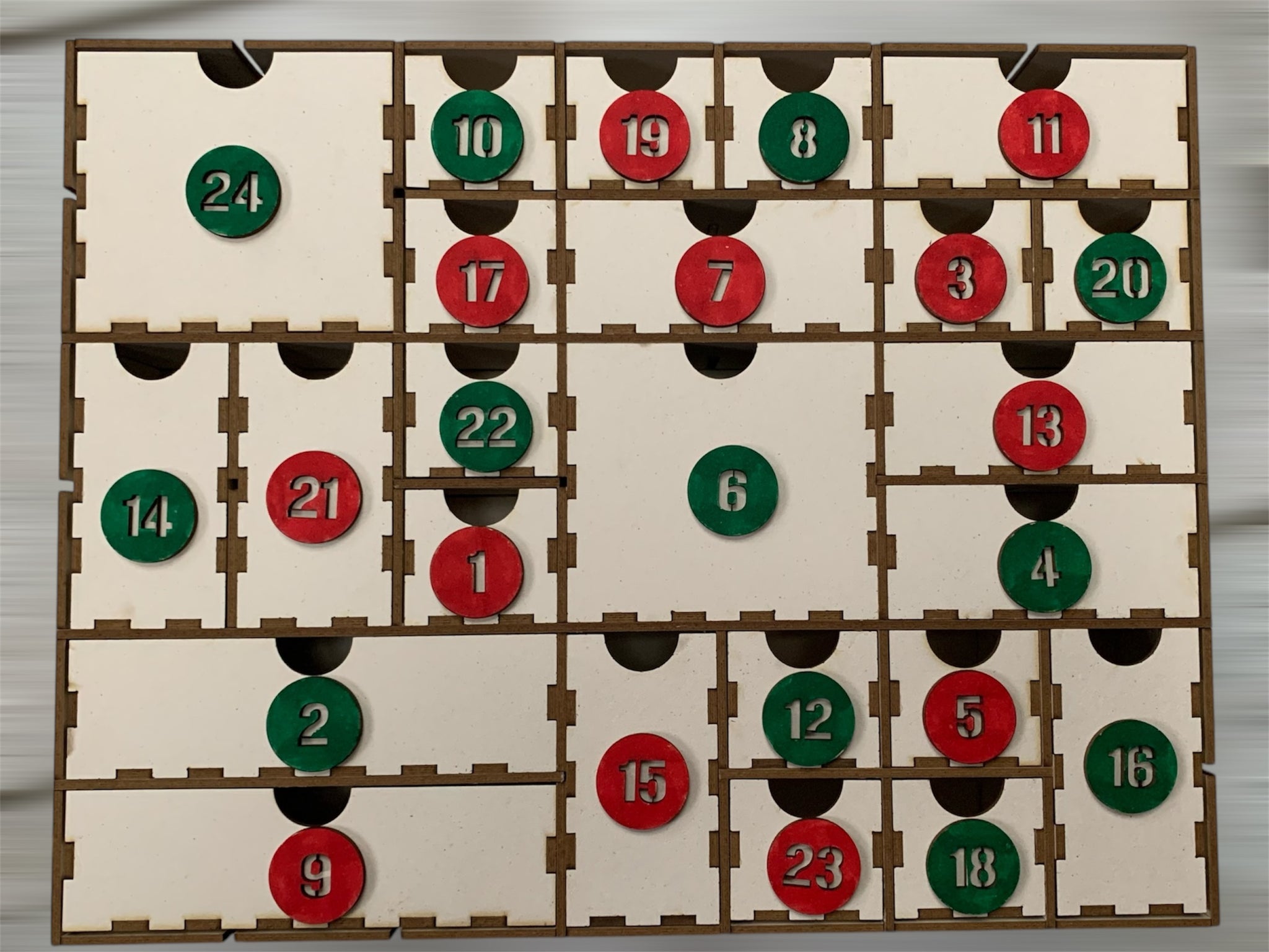 Bunter 3 mm Adventskalender von easy-sticks mit roter und grüner Nummerierung in den Schubladen, wartet auf persönliche Gestaltung mit Geschenken.