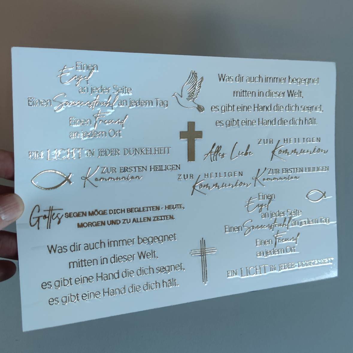 Rub on UV Sticker randlos Gold Sprüche Kommunion/ Konfirmation/ Taufe A5 von easy-sticks, in der Hand gehalten, präsentiert elegante Schriftzüge und christliche Symbole in edlem Gold.