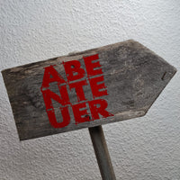 Wegweiser aus Holz mit dem auffälligen Aufdruck 'ABENTEUER' in Rot, inspiriert von der Abenteuer Laserdatei von easy-sticks.