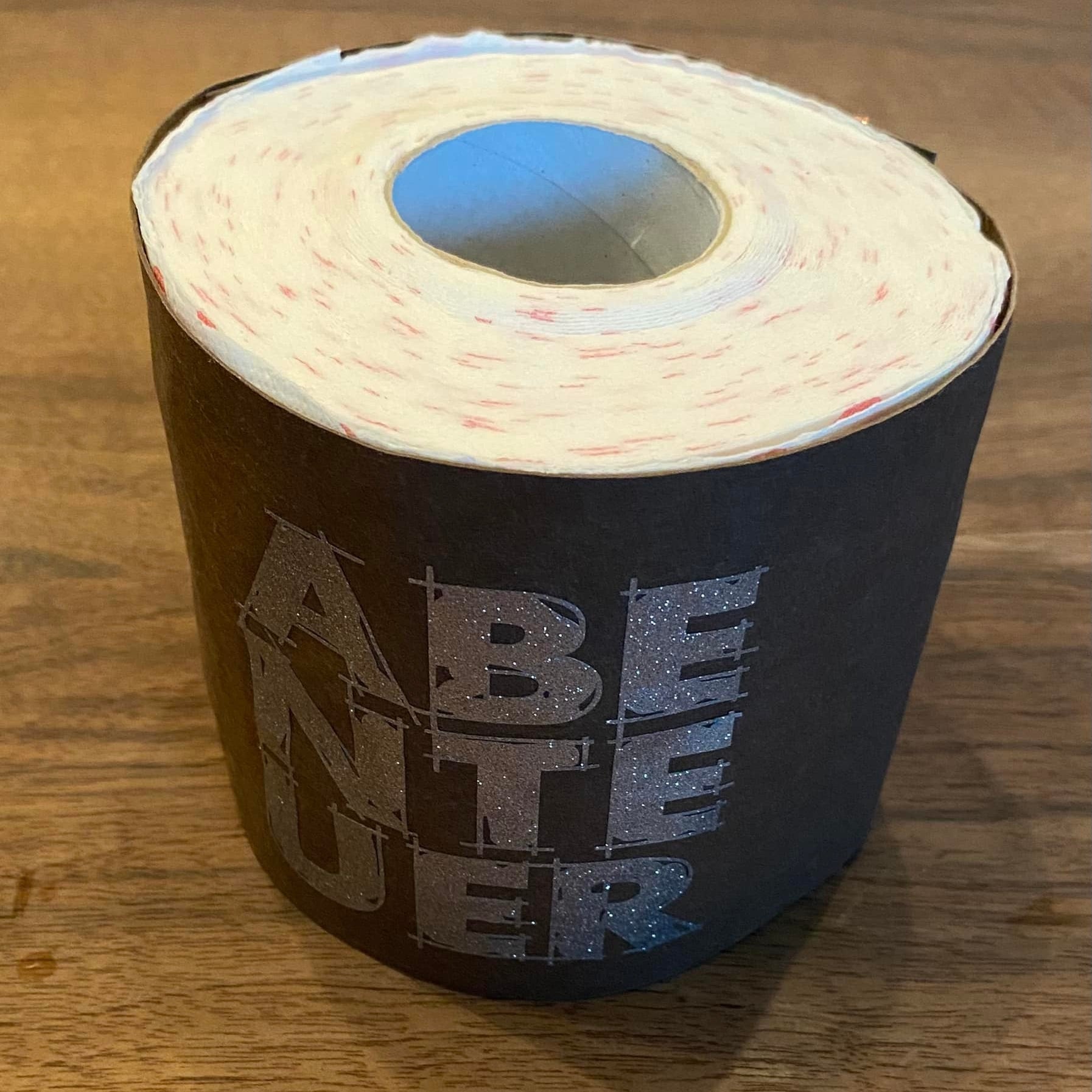 Originelle Rolle mit Toilettenpapier, verziert mit dem Wort 'ABENTEUER' in Glitzerdesign, inspiriert durch die Laserdatei 'Abenteuer' von easy-sticks.