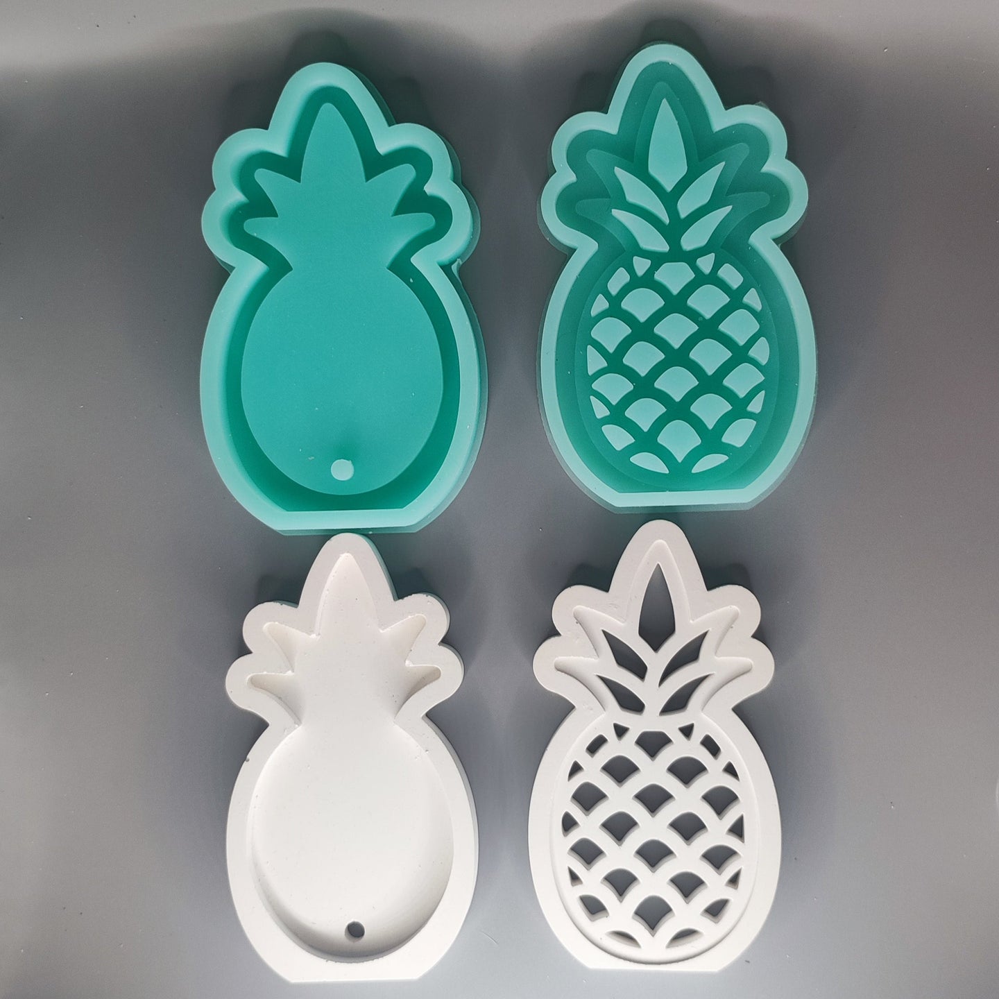 Zwei Silikonformen in Ananasform von Easy-Sticks, eine mintgrüne und eine weiße, perfekt für kreative DIY-Projekte.