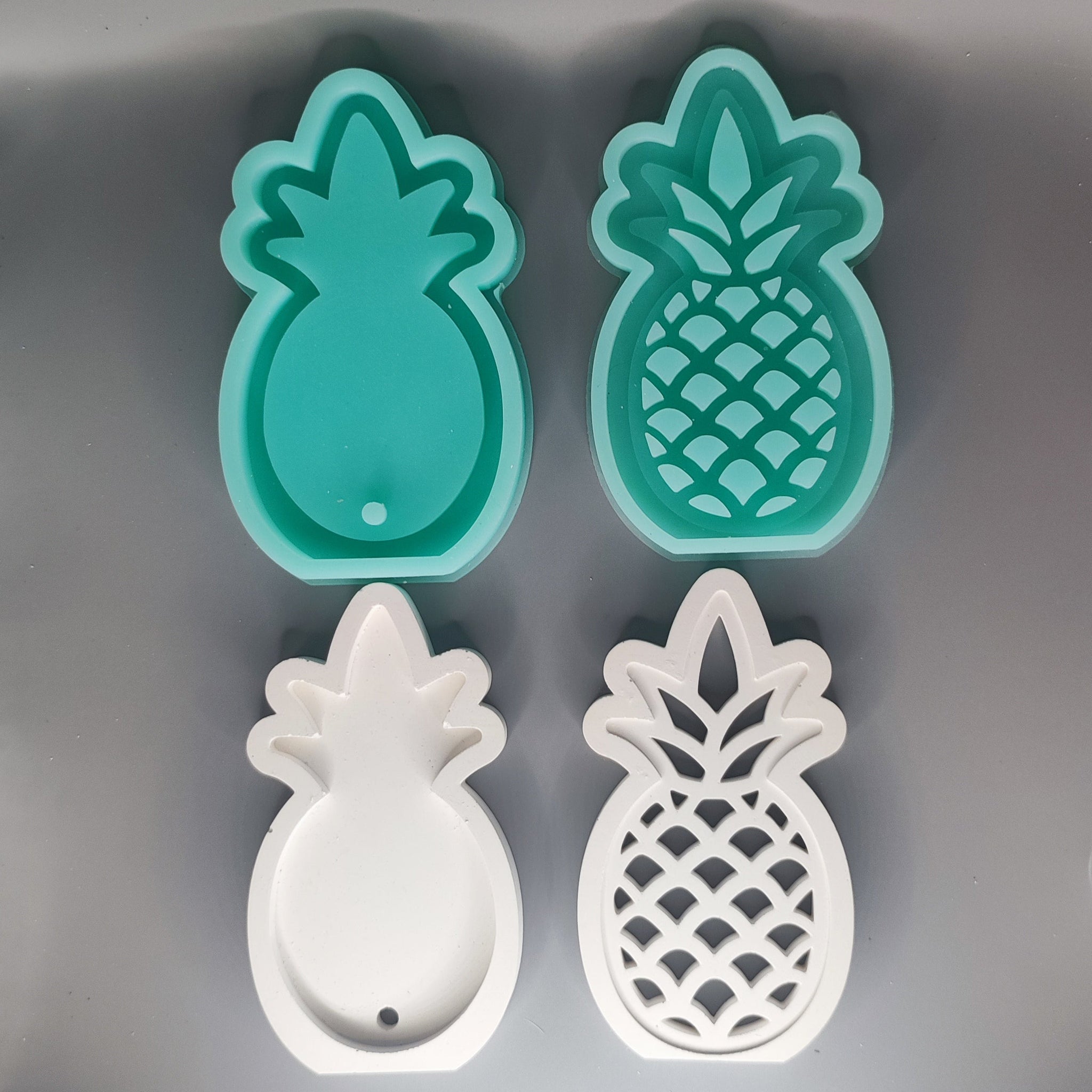Zwei Silikonformen in Ananasform von Easy-Sticks, eine mintgrüne und eine weiße, perfekt für kreative DIY-Projekte.