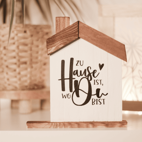 Stilvolles Holzhaus mit dem Spruch 'Zu Hause ist, wo Du bist', perfekt für persönliche Dekorationen. Plotter- und Laserdatei von easy-sticks.