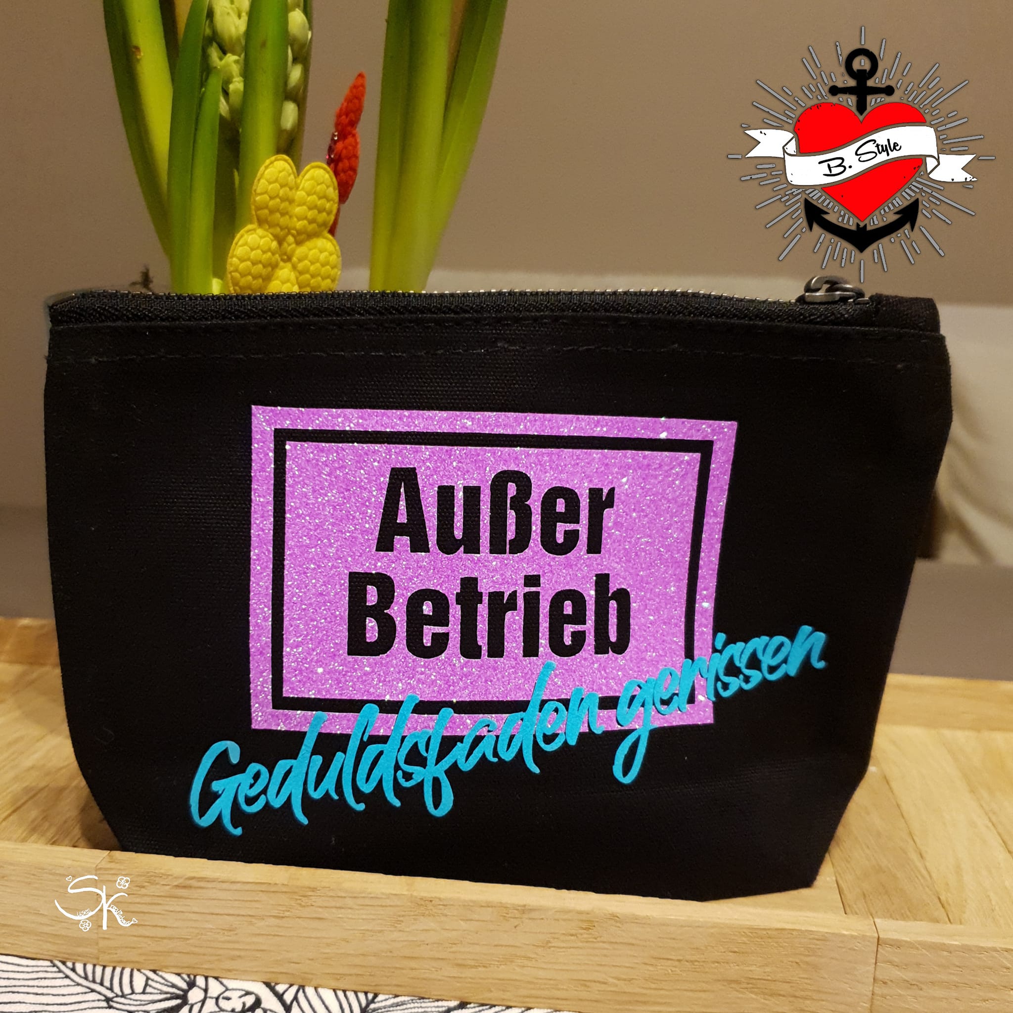 Schminktäschchen mit der "Außer Betrieb - Geduldsfaden gerissen" Laserdatei von easy-sticks, verziert mit glitzerndem lila Hintergrund und türkisfarbener Schrift.