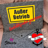 Kreatives Beispiel für die "Außer Betrieb - Geduldsfaden gerissen" Laserdatei von easy-sticks, präsentiert auf einer grauen Filztasche mit gelbem Schild und rotem Schriftzug.