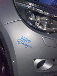 Nahaufnahme eines grauen Autos mit dem Aufdruck "Blitzer Testwagen". Verwende die Auto Sprüche Plotterdatei von easy-sticks, um dein Fahrzeug individuell zu gestalten.