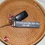 Ein Schlüsselbund liegt in einem Korb mit einem Schlüsselanhänger von easy-sticks, der den Spruch "Ich muss kein altes Auto fahren, Ich will" trägt. Auto Sprüche Plotterdatei.