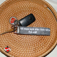 Ein Schlüsselbund liegt in einem Korb mit einem Schlüsselanhänger von easy-sticks, der den Spruch "Ich muss kein altes Auto fahren, Ich will" trägt. Auto Sprüche Plotterdatei.