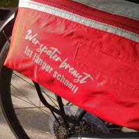 Rotes Fahrradtaschen-Design mit dem Spruch "Werspäter bremst, ist länger schnell". Nutze die kreative Auto Sprüche Plotterdatei von easy-sticks für deine eigenen Designs.