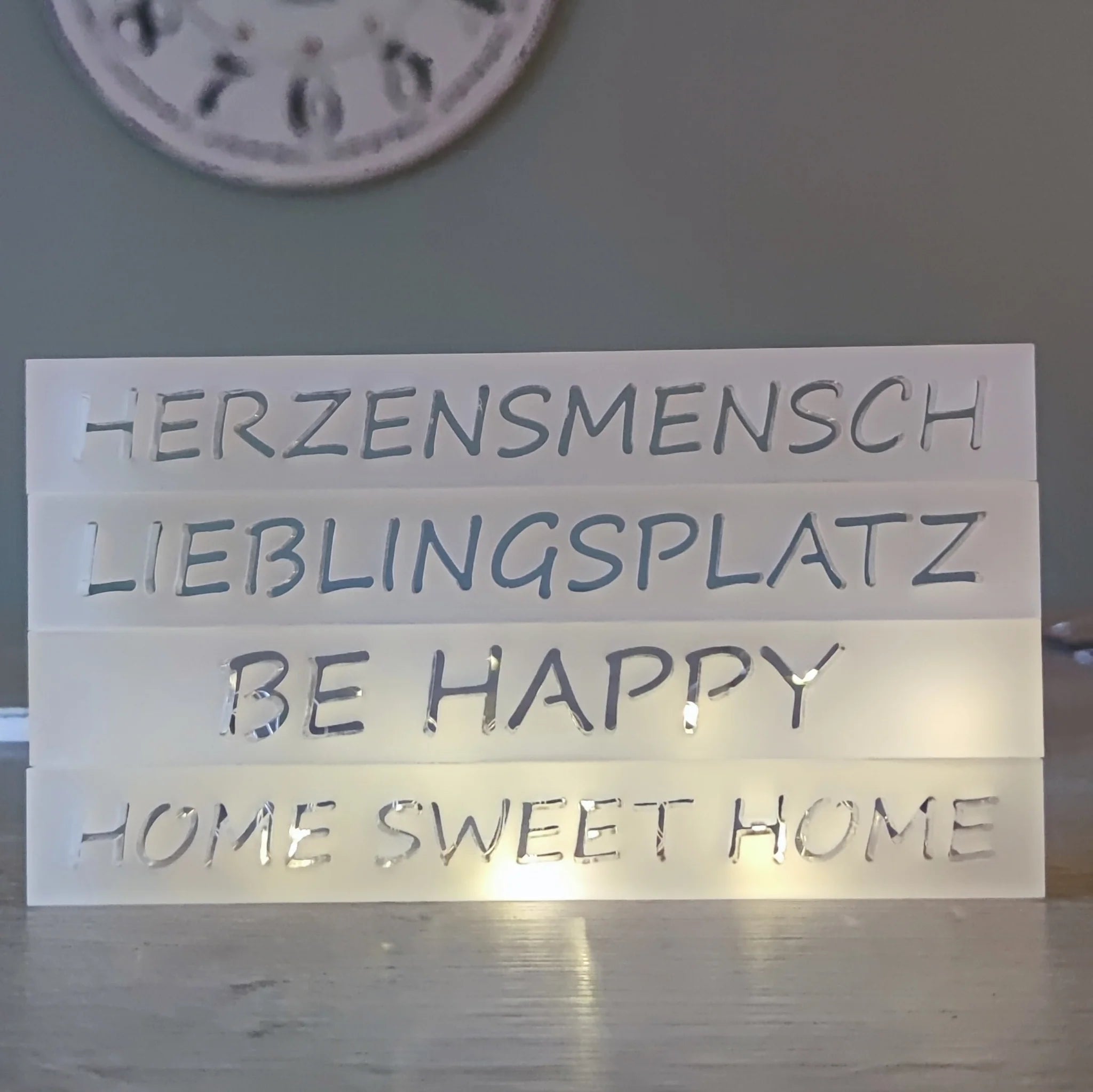 Eine stilvolle Präsentation von Acryl Easy-Sticks mit den eingravierten Worten 'HERZENSMENSCH', 'LIEBLINGSPLATZ', 'BE HAPPY' und 'HOME SWEET HOME', ideal für Dekoration und kreative DIY-Projekte von Easy-Sticks Acryl Satiniert.