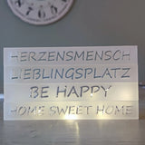 Kreative Anordnung der Acryl Easy-Sticks 'HERZENSMENSCH', 'LIEBLINGSPLATZ', 'BE HAPPY' und 'HOME SWEET HOME' von Easy-Sticks, stimmungsvoll beleuchtet.
