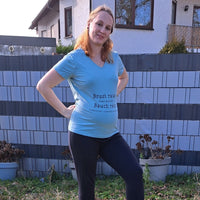 Schwangere Frau in einem blauen T-Shirt mit einem humorvollen weiblichen Spruch von easy-sticks, die ihren Babybauch zeigt.