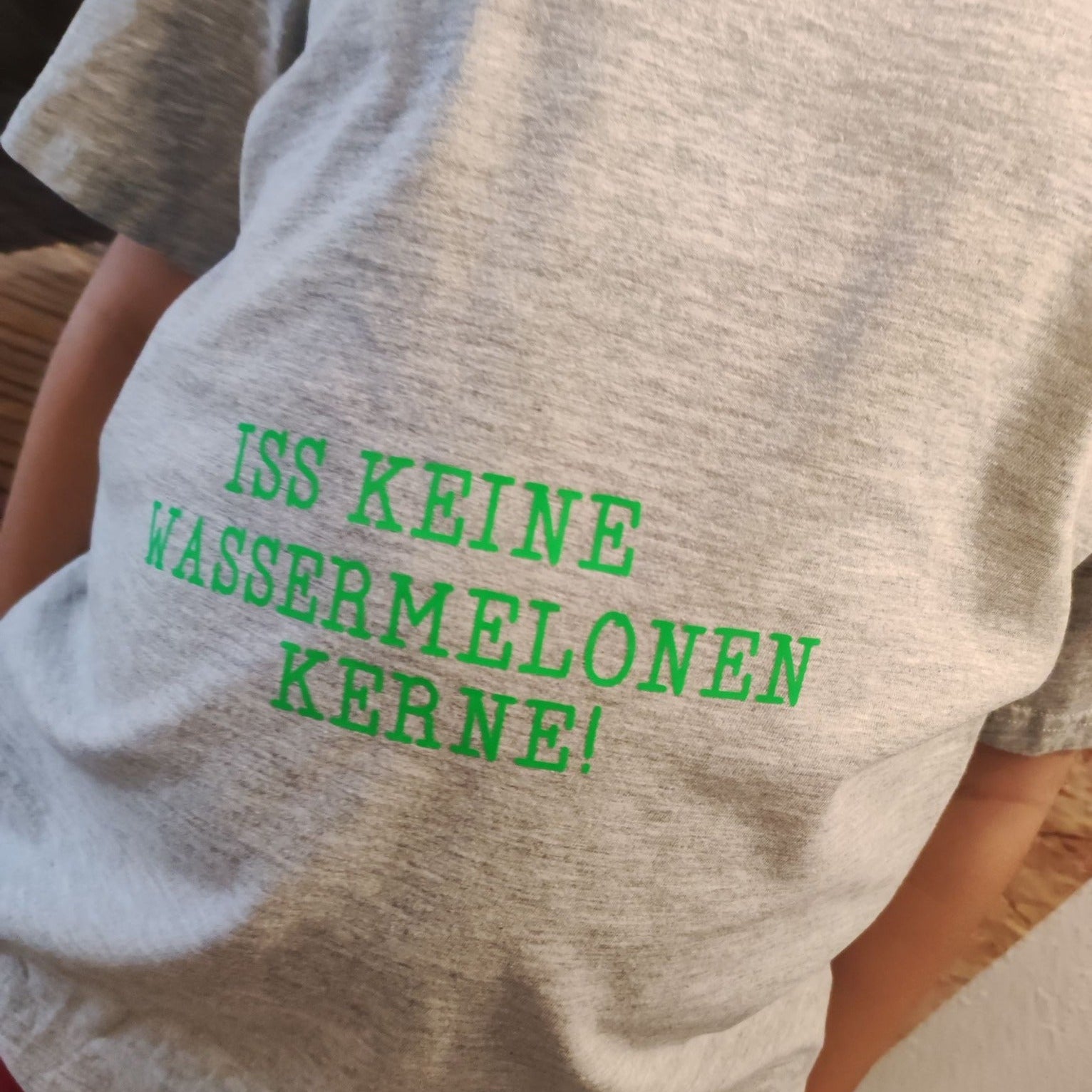 Ein graues T-Shirt für Kinder mit dem Aufdruck 'ISS KEINE WASSERMELONEN KERNE!', perfekt für DIY-Projekte - Babybauch Plottersprüche Datei von easy-sticks.