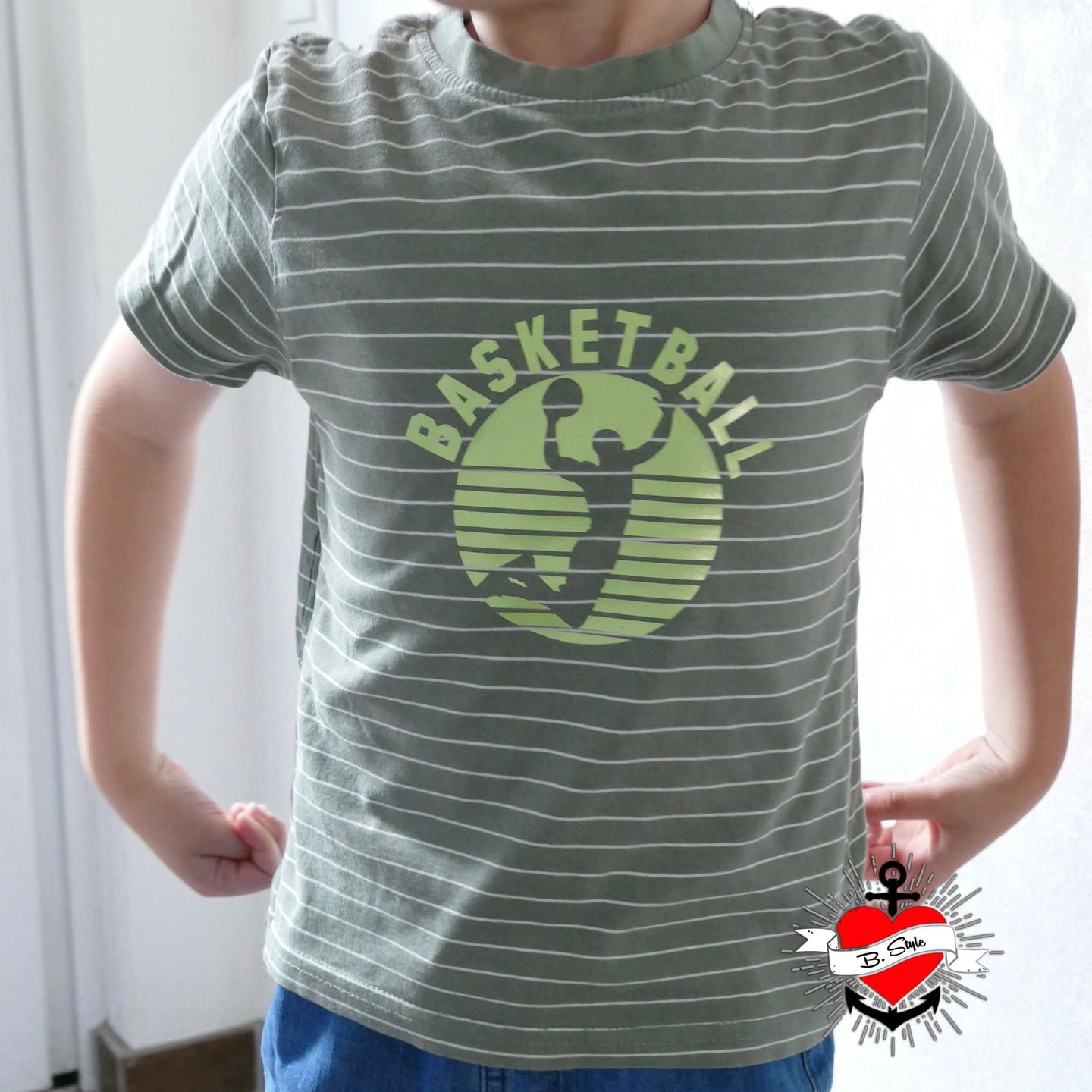 Kind trägt ein T-Shirt mit einem Basketball-Plotterdatei-Design von easy-sticks, das die Silhouette eines springenden Basketballspielers und das Wort 'Basketball' zeigt, perfekt für sportliche Outfits.