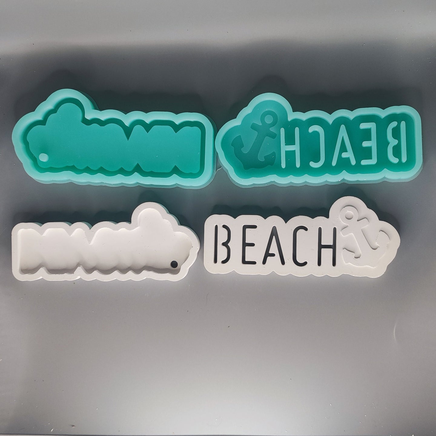 Zwei Silikonformen von Easy-Sticks für das Gießen von Dekoartikeln, einschließlich der Form "BEACH mit Anker" in verschiedenen Farben.