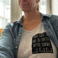 Frau trägt ein Shirt mit dem Aufdruck "MAN SAGT JA VIEL ZU SELTEN BITTE. DANKE." von easy-sticks, betont den individuellen Stil.