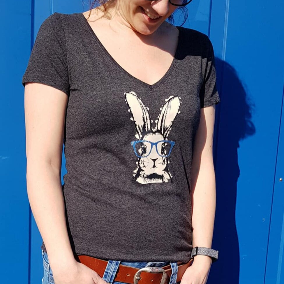 Dame in einem schwarzen V-Ausschnitt T-Shirt, das mit dem Bunny Hasen Design von easy-sticks bedruckt ist, zeigt einen bunten Hasen mit Brille.