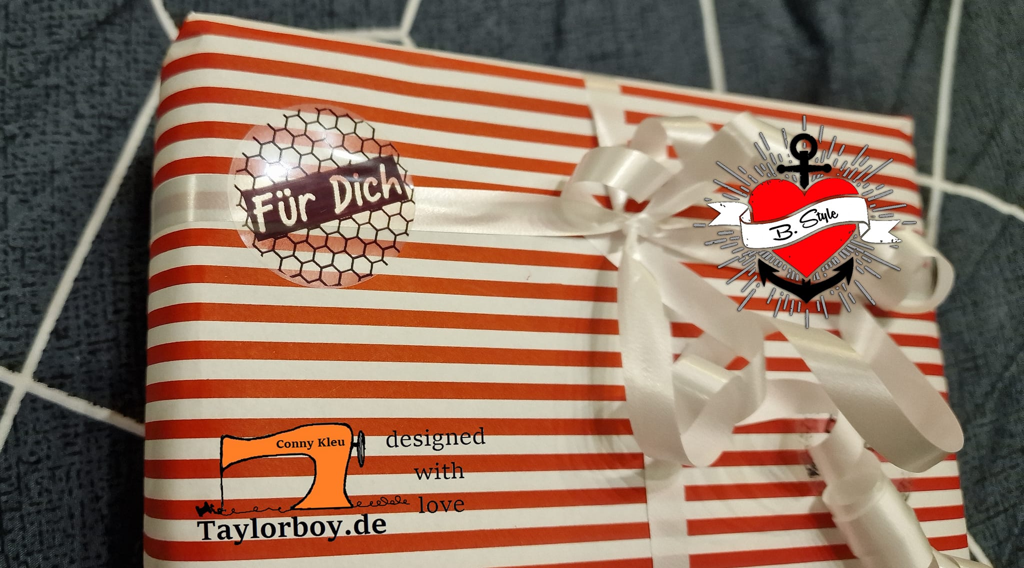 Ein liebevoll verpacktes Geschenk mit einem Button-Aufkleber "Für Dich" und einem weißen Schleifenband, das die kreative Note des Designs von easy-sticks zeigt. Die Geschenkverpackung ist mit roten und weißen Streifen gestaltet, was das Farbschema harmonisch ergänzt. Ideal für persönliche Geschenke.