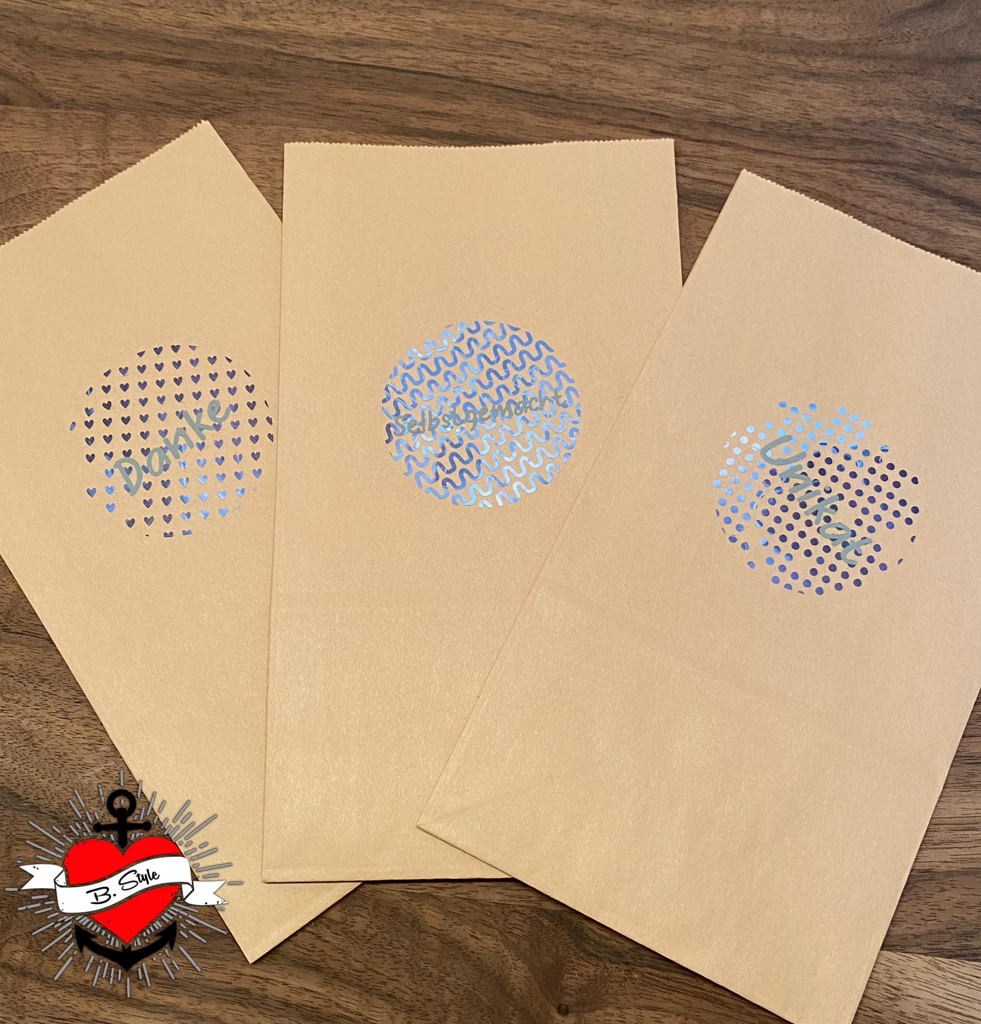 Drei beige Tüten mit hochwertigen Button-Dekorationen, bedruckt mit den Worten 'Danke', 'Selbstgemacht' und 'Unikat', ideal für kreative Geschenkideen – Button Plotterdatei von easy-sticks.