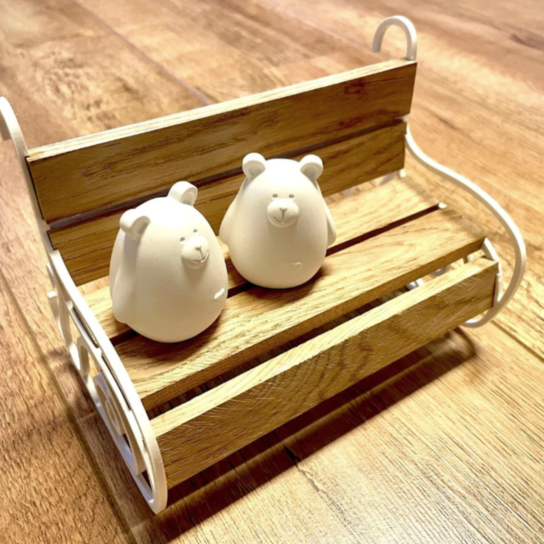 Zwei niedliche Bärenfiguren auf einer Holzschaukel. Die Seitenteile sind aus dem 3D Drucker gedruckt mit der Datei zum Kaufen und Downloaden. Ideal für 3D-Druck-Projekte und zur Personalisierung von Bänken.