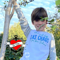 Ein fröhlicher Junge, der unter einem Baum steht, trägt ein T-Shirt mit 'DAS CHAOS'. Kreatives Design von easy-sticks!