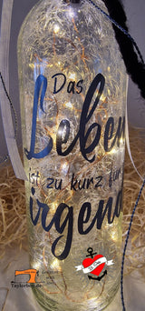 Beleuchtete Flasche mit der Plotterdatei "Das Leben ist zu kurz für irgendwann" von easy-sticks, die ein kreatives Ambiente schafft.