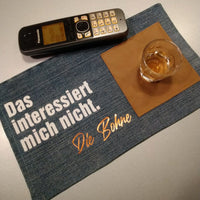 Das interessiert mich nicht. Die Bohne Plotterdatei von easy-sticks, dargestellt auf einem Tisch mit einem Telefon, einem Glas und einem Platzdeckchen aus Stoff, das kreativ gestaltet ist.