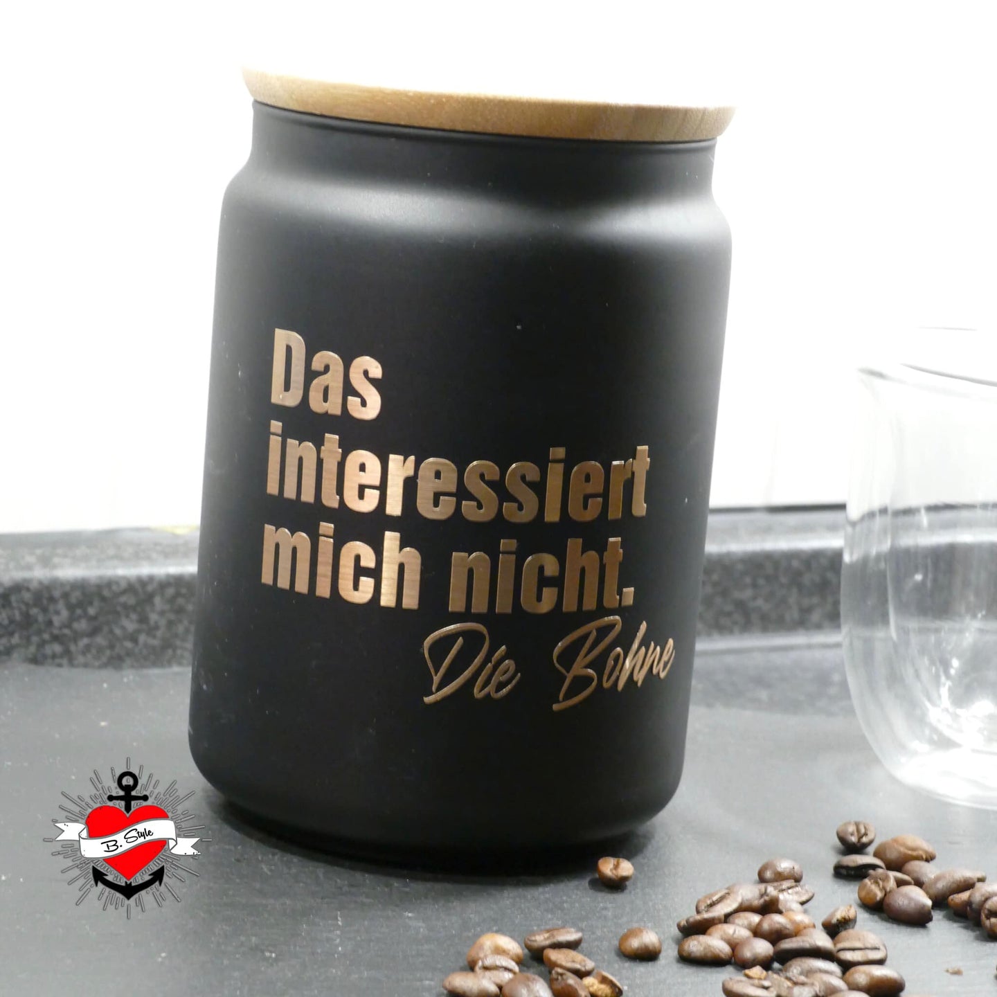 Schwarzer Metallbehälter mit Holzdeckel, darauf steht in goldener Schrift: "Das interessiert mich nicht. Die Bohne". Perfekt für kreative Projekte, erhältlich bei easy-sticks.