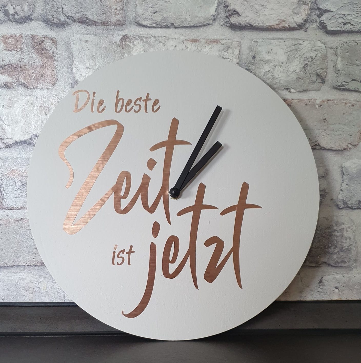 Wanduhrenkreation mit dem Titel "Die beste Zeit ist jetzt" von easy-sticks, auf hellem Hintergrund zeigt sie die stilvolle Zeitansage in einer modernen Schriftart.