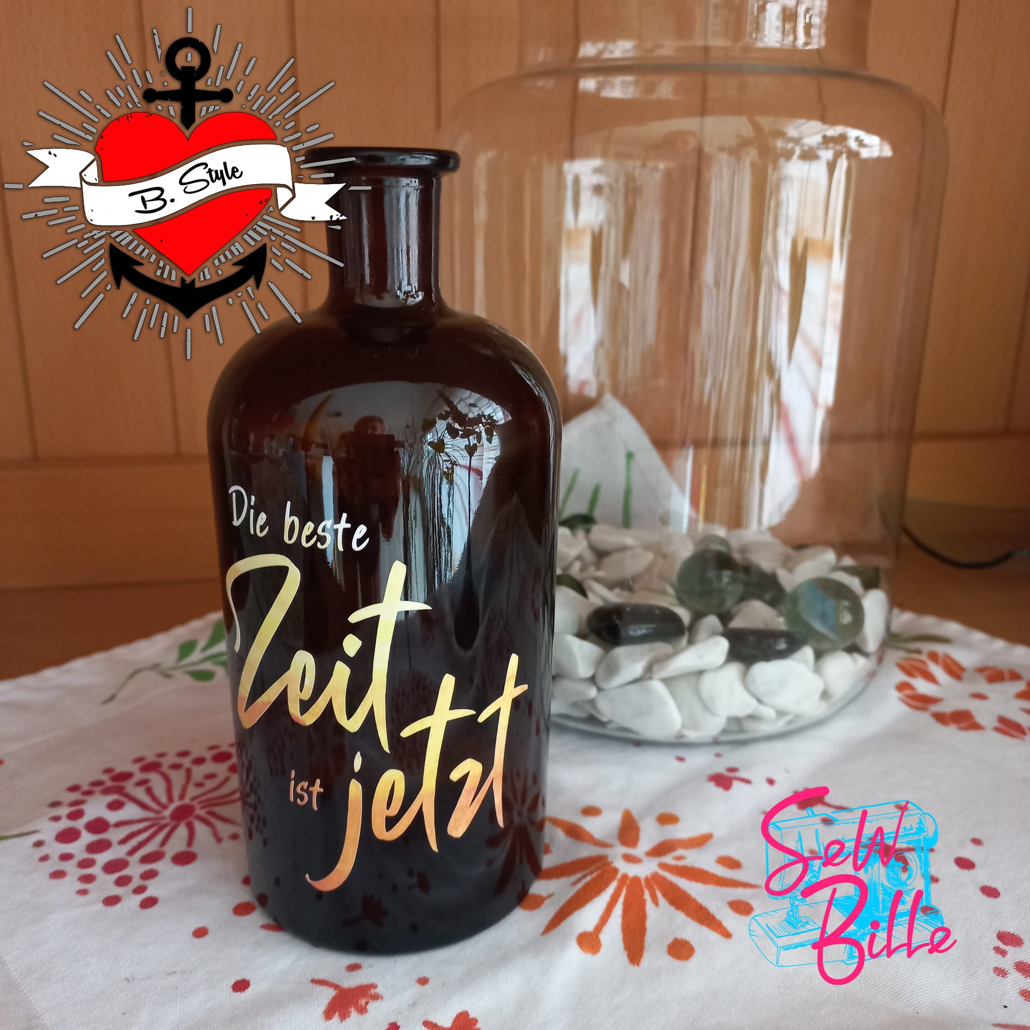Eine stilvolle Flasche mit dem Aufdruck "Die beste Zeit ist jetzt" von easy-sticks, setzt farbige Akzente und ergänzt jede kreative Dekoration.