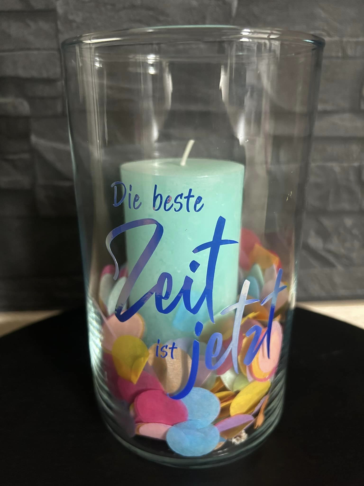 Ein Glasbehälter gefüllt mit bunten Konfettiherzen und einer blauen Kerze, beschriftet mit "Die beste Zeit ist jetzt" von easy-sticks, perfekt für festliche Anlässe.
