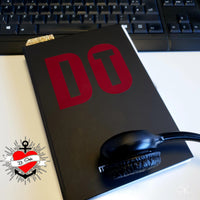 Inspirierende Aufnahme eines Notizbuchs mit der "DO IT" Plotterdatei von easy-sticks, auf einem Schreibtisch, neben einem Kopfhörer, bereit für kreative Projekte und individuelle Designs.