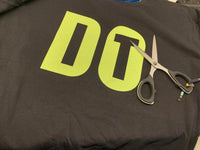 "DO IT" Plotterdatei von easy-sticks auf einem T-Shirt, versehen mit einem leuchtenden Design, das kreative DIY-Projekte anregt, daneben eine Schere zum Schneiden.