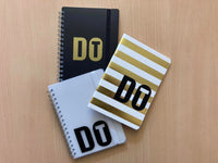 Drei Notizbücher mit kreativem "DO IT" Design von easy-sticks auf einem holzfarbenen Tisch, perfekt für kreative Notizen und Planungen.